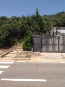 una valla y una puerta al costado de una carretera en Battistina Holiday Home, en Monte Nai