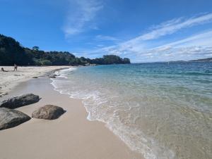 a beach with rocks in the sand and the water at A Casiña Laranxa in Cangas de Morrazo