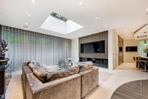 a living room with a large couch and a television at Luxurious subterranean mansion - 3 spectacular bedrooms in Altrincham