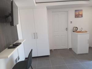 a white kitchen with a white door and a black chair at Lefa Guesthouse in Ledig