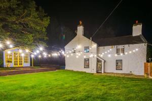 a white house with lights on a yard at night at Mochdre Holiday Cottages in Mochdre