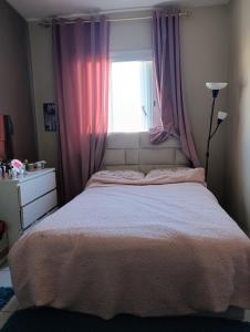 a bedroom with a bed and a window with pink curtains at Logement tout confort, équipé ! in Casablanca