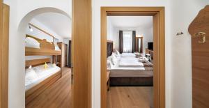 a bedroom with two beds and an open doorway at Family Hotel Posta in Santa Cristina in Val Gardena +46 photos