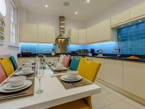 ラムズゲートにある4 Bed in Ramsgate 86741の長いテーブルと椅子、そして青いタイルが敷かれたキッチン