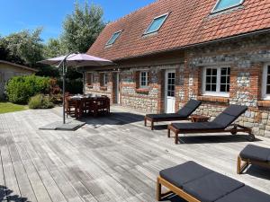 a patio with two chairs and an umbrella and a table at Longère Normande in Sainte-Marguerite