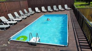 a person swimming in a swimming pool with chairs at Bilychi - садиба у Карпатах in Bilichi