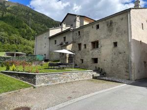 a large building with a table and an umbrella at Cá da l'Albina in Prada