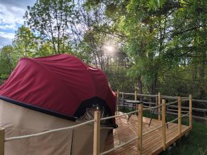 a tent with a red cover on a wooden deck at Friendly Camping and Lodges in Saint-Pardoux-la-Rivière