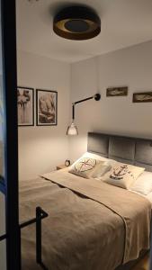 a bedroom with a bed with a lamp and pictures on the wall at Apartament na wydmie B9 in Łeba