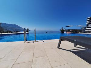a bench sitting in front of a swimming pool at Skyline sea view apartment in Bečići +12 photos