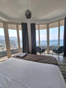 a bedroom with a bed and some chairs and windows at Skyline sea view apartment in Becici