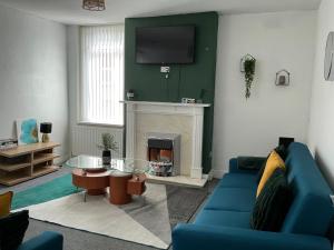 un salon avec un canapé bleu et une cheminée dans l'établissement Humble Home NE - Short & Long stay or Contractors, à Gateshead