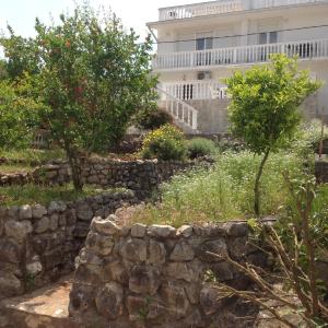a stone wall and trees in front of a building at Guest House "Paradise" in Tivat