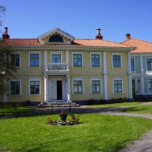 ein großes gelbes Haus mit einer Veranda auf einem Rasen in der Unterkunft Kalmar Sjömanshem in Kalmar