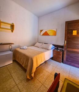 a bedroom with a bed and a wooden door at POUSADA MANACÁ DA SERRA in Vargem Bonita