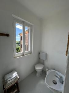 a white bathroom with a toilet and a window at Panorama nel borgo in Monteciccardo