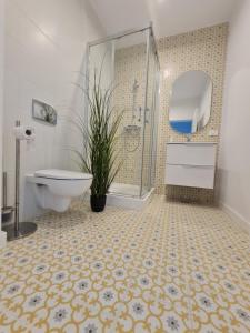 a bathroom with a shower and a toilet and a plant at Residence Sole by Axxis Nova Resort - Apartament luxury 70mp cu terasa si vedere la mare, acces direct pe plaja Axxis Beach BluFlag - Mamaia Nord - Parcare gratuita in Mamaia +61 photos