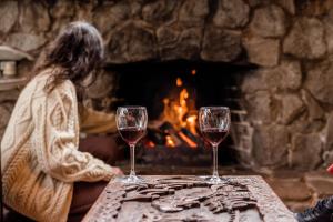 two glasses of wine on a table in front of a fireplace at Dreamers Mt Beauty in Mount Beauty