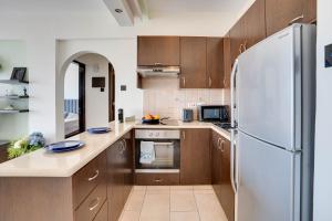 a kitchen with wooden cabinets and a refrigerator at Glabur Stays! The One -1 - Elite Marina Front! in Zygi
