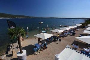 a beach with umbrellas and people in the water at Garten House in Kornić +1 photo
