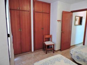 una camera da letto con armadi in legno e una sedia accanto al letto di adosado a 50m de la playa el cargador a Castellón de la Plana