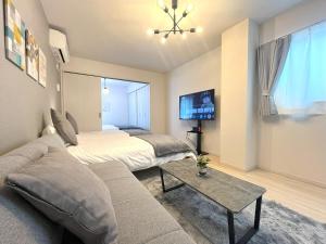 a living room with a couch and a bed and a tv at Naos House Hotel Osaka 5 in Osaka +39 photos
