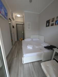 a small bedroom with a white bed and wooden floors at Eva Beach Studio in Néa Péramos
