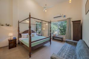 a bedroom with a four poster bed and a couch at SaffronStays Roselle, Malavli - pet-friendly pool villa with modern interiors in Lonavala +18 photos