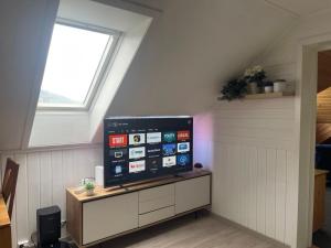 a tv sitting on a cabinet in a room with a window at Arctic Skyview Retreat in Tromso - with parking in Tromsø