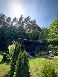 een klein zwart huis in een tuin met bomen bij Sarzynówka pod Sosną in Krasnobród