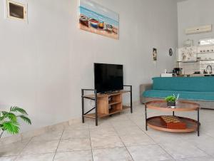 a living room with a blue couch and a tv at Old Cafe Apartment in Skala Kallirachis