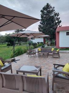 a patio with benches and tables and an umbrella at Hôtel La Cuenda Sochatour in Arbaoua