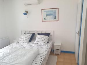 1 cama blanca con almohadas y una foto en la pared en chez Marcel, en Rosières