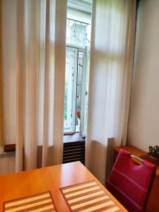 a wooden table with a red chair next to a window at Garden Apartment in Brno