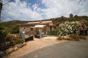 una pequeña casa de ladrillo con porche y flores en Au Pont De Tuarelli, Ludique, Fango, en Manso