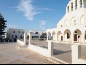 a white building in a parking lot at Mitropolis Apartment in Naxos Chora