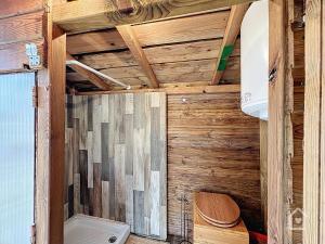a bathroom with a wooden wall with a toilet at Yourte nature & calme proche Futuroscope in Archigny