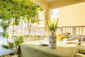 a table with a vase with yellow flowers on it at Olea House in Lukoran +18 photos