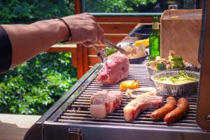 a person is cooking meat and vegetables on a grill at 100度越えサウナ,森林浴,絶景パノラマビュー,森の中の隠れ家,星見ジャグジー---ハーミットたいとう--- in Shiigi
