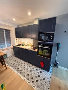 a kitchen with black cabinets and a stove top oven at Maison Sorbier, Appartement 1 in Nevers