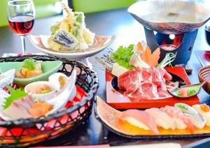 un tavolo con piatti di cibo e un bicchiere di vino di LiVEMAX RESORT Hakone Sengokuhara a Hakone
