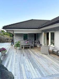 a wooden deck with a table and chairs on a house at Fint hus med havsutsikt, stor terrass och med parkeringsplatser in Svanesund