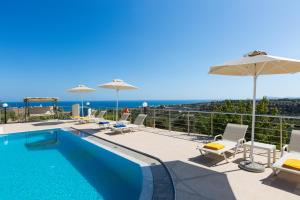 una piscina con sillas y sombrillas y el océano en Diamantis Villa, a SeaView Retreat, By ThinkVilla, en Adelianos Kampos