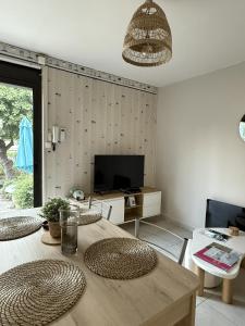 a living room with a wooden table and a television at Sabl'Appart Gare in Les Sables-d'Olonne