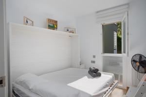 ein weißes Schlafzimmer mit einem Bett und einem Fenster in der Unterkunft Apartament gran amb vistes al mar, piscina i pàrquing in Calella de Palafrugell