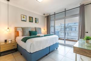 una camera da letto con un letto grande e una grande finestra di Exquisite Emerald Stay at Ridgeton Modern Two Bedroom Apartment in the Heart of Umhlanga Ridge Sleeps 6 a Durban