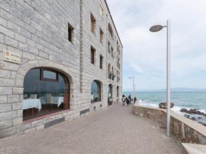 レスカラにあるBelvilla by OYO Albatros 6の歩道を歩く人々のいる海の隣のレンガ造りの建物