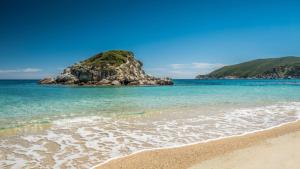 a beach with a small island in the ocean at Suite di Lusso in Kalamitsi