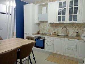 a kitchen with white cabinets and a wooden table at Nerea Apartment in SantʼAgata di Militello
