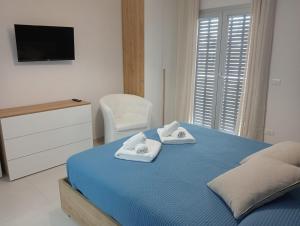 a bedroom with a blue bed with towels on it at Nerea Apartment in SantʼAgata di Militello